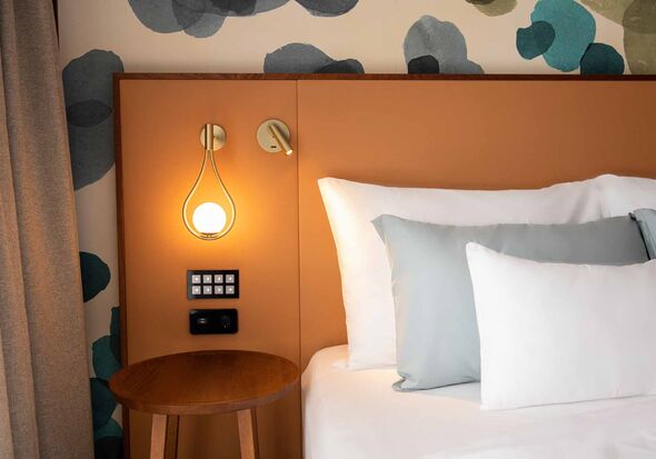 3 cushions on the bed with bedside lamp on