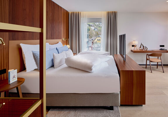 Bett mit TV, Kommode und Schreibtisch im Zimmer Königsforelle