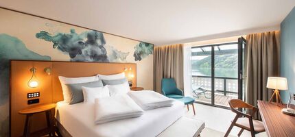 Großes Doppelbett im Hotelzimmer mit Balkon mit Seeblick