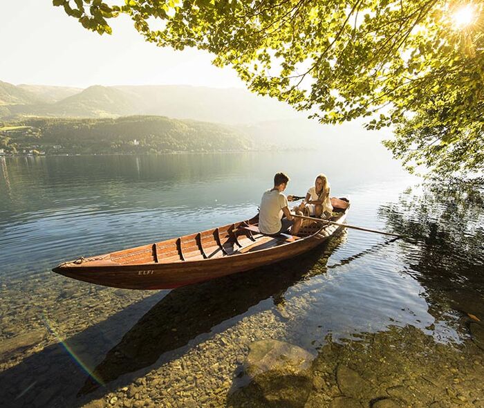 A couple navigates the romantic Lake Millsätter in a wooden rowing boat
