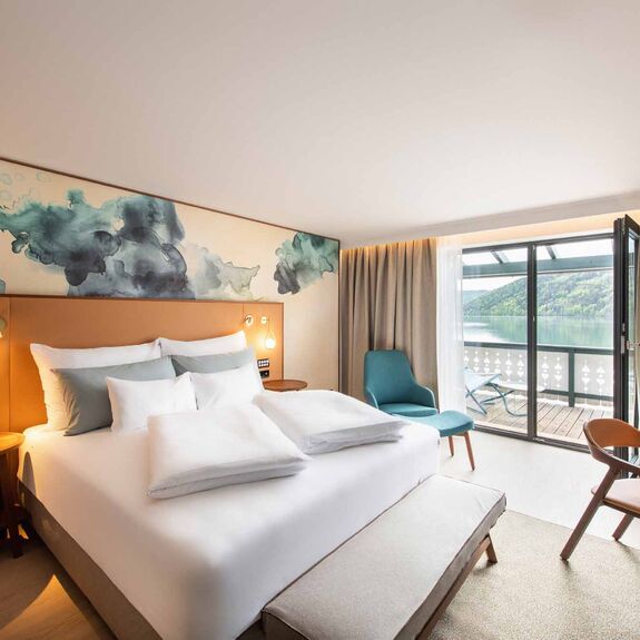Großes Doppelbett im Hotelzimmer mit Balkon mit Seeblick