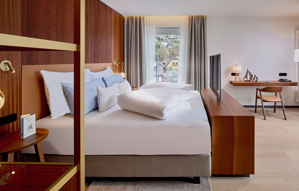 Bett mit TV, Kommode und Schreibtisch im Zimmer Königsforelle