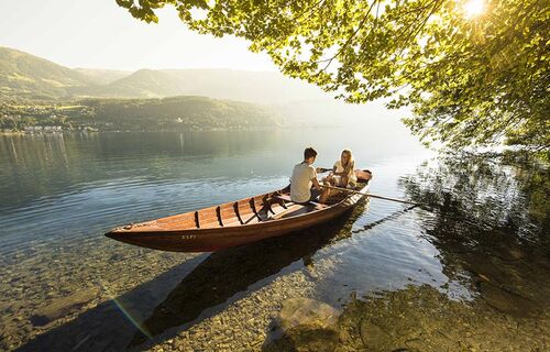 Ein Paar befährt den romantischen Millsättersee mit einem hölzernen Ruderboot