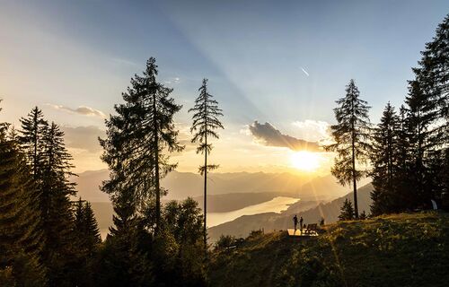 Ein Paar bewundert bei einer kurzen Pause auf einem Berg den Ausblick auf den von der goldenen Abendsonne beschienenen Millstättersee