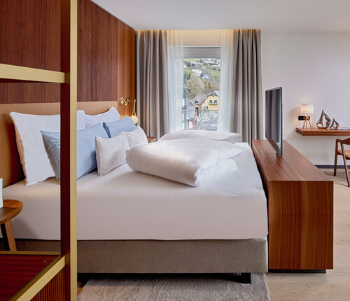 Bett mit TV, Kommode und Schreibtisch im Zimmer Königsforelle