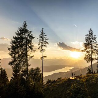 Ein Paar bewundert bei einer kurzen Pause auf einem Berg den Ausblick auf den von der goldenen Abendsonne beschienenen Millstättersee