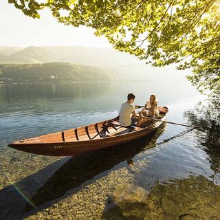 Ein Paar befährt den romantischen Millsättersee mit einem hölzernen Ruderboot