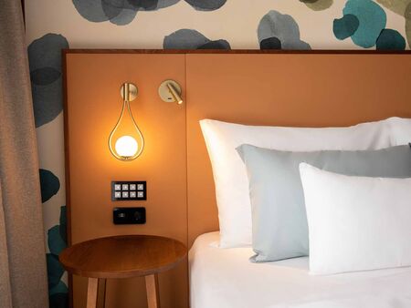 3 cushions on the bed with bedside lamp on