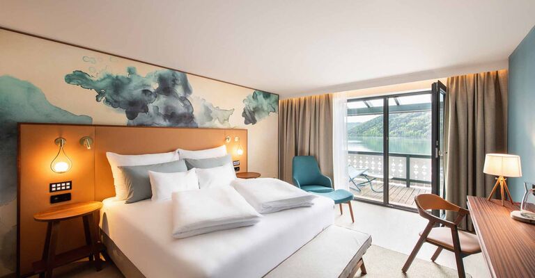 Großes Doppelbett im Hotelzimmer mit Balkon mit Seeblick