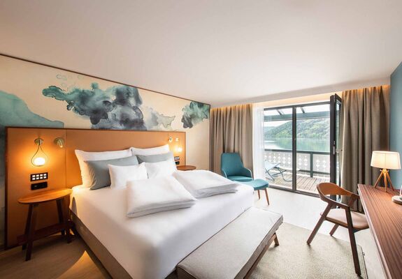 Großes Doppelbett im Hotelzimmer mit Balkon mit Seeblick