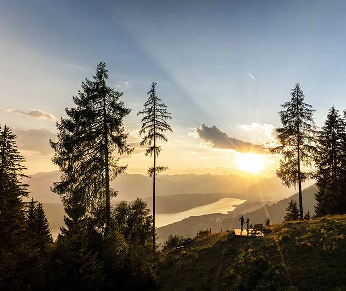 Ein Paar bewundert bei einer kurzen Pause auf einem Berg den Ausblick auf den von der goldenen Abendsonne beschienenen Millstättersee