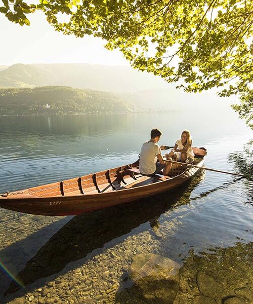 A couple navigates the romantic Lake Millsätter in a wooden rowing boat