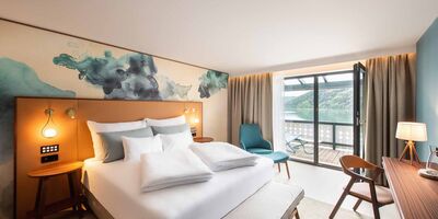 Großes Doppelbett im Hotelzimmer mit Balkon mit Seeblick