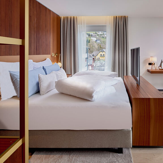 Bett mit TV, Kommode und Schreibtisch im Zimmer Königsforelle