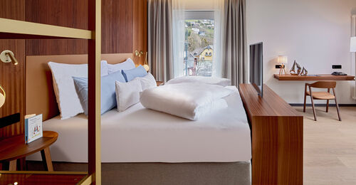 Bett mit TV, Kommode und Schreibtisch im Zimmer Königsforelle