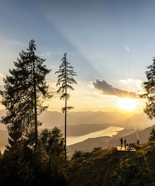 Ein Paar bewundert bei einer kurzen Pause auf einem Berg den Ausblick auf den von der goldenen Abendsonne beschienenen Millstättersee