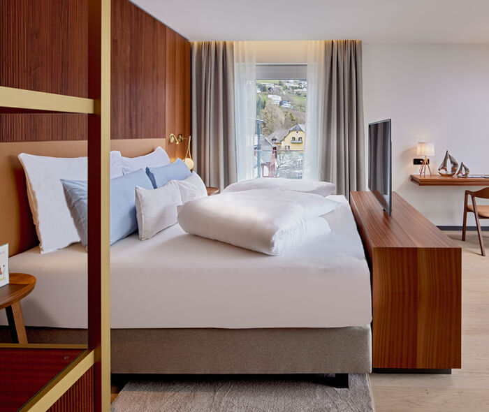 Bett mit TV, Kommode und Schreibtisch im Zimmer Königsforelle