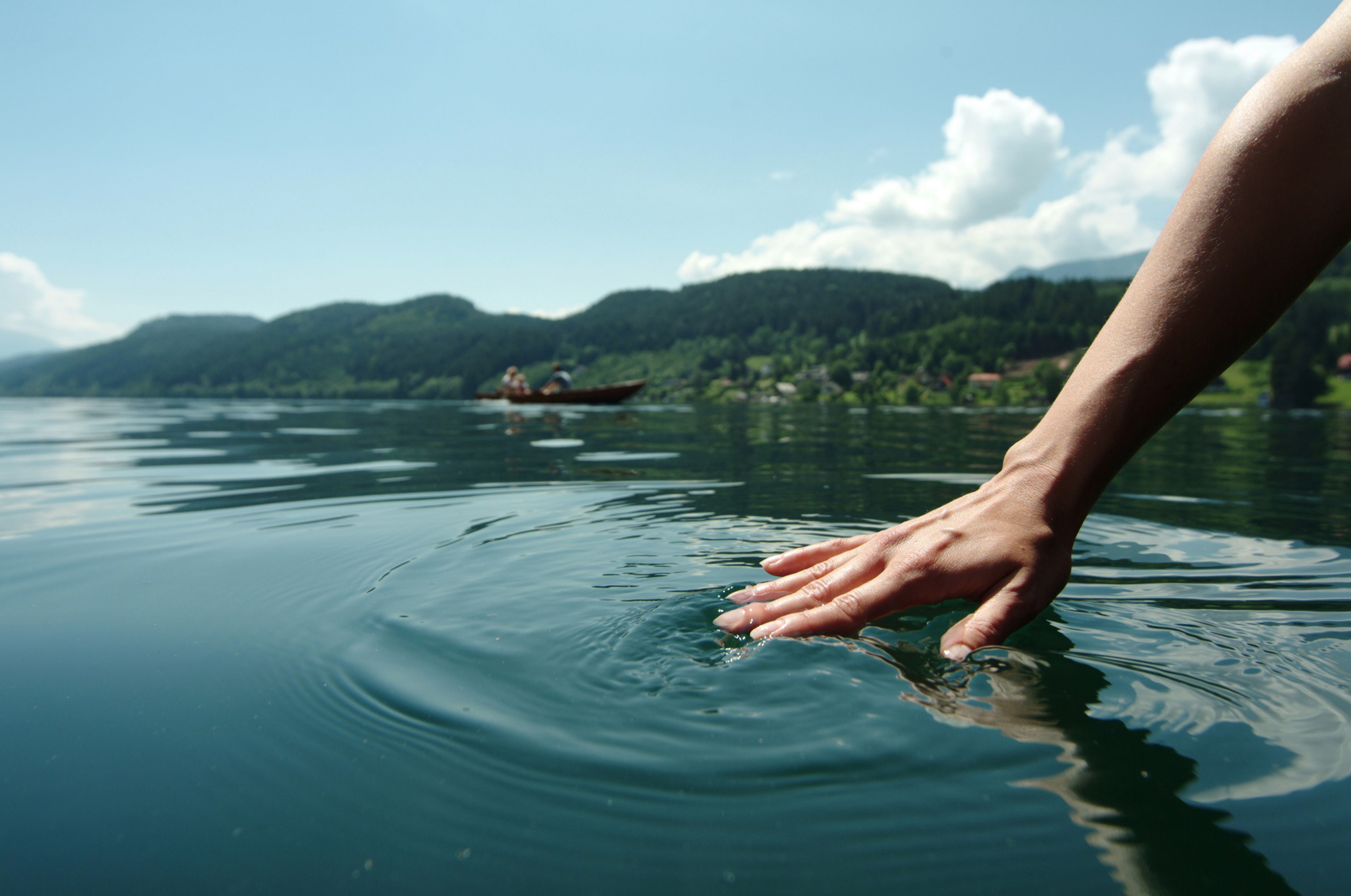 Hand berührt Wasser des Sees