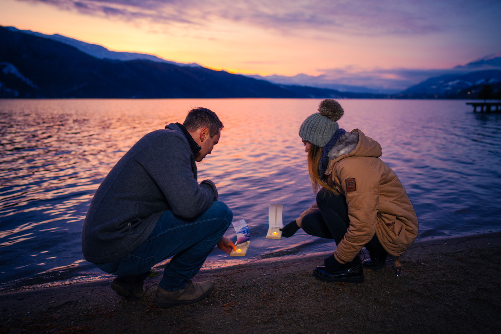 Paar im Abendlicht am Ufer hockend