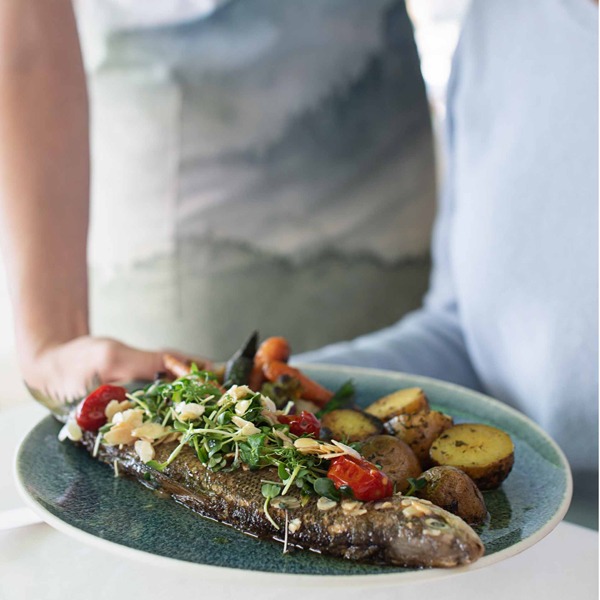 Waiter serves guest freshly prepared fish