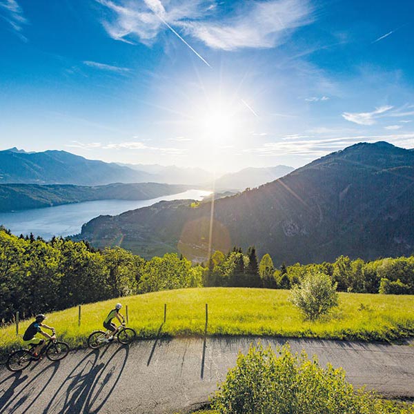 Two cyclists riding by Lake Millstätter See.
