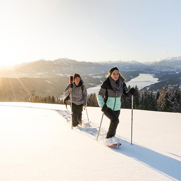 Zwei Personen beim Schneeschuhwandern im Hintergrund der Millstätter See