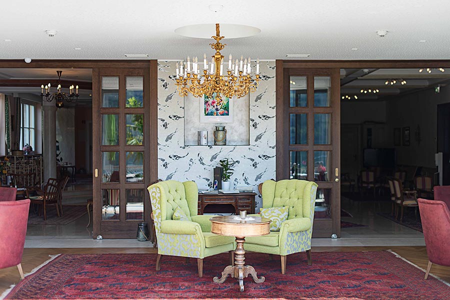 2 elegant chairs in the middle of the room with a majestic chandelier