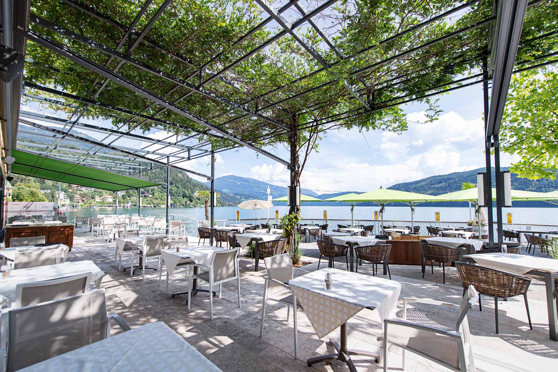 Sun terrace with shady trees and covered tables